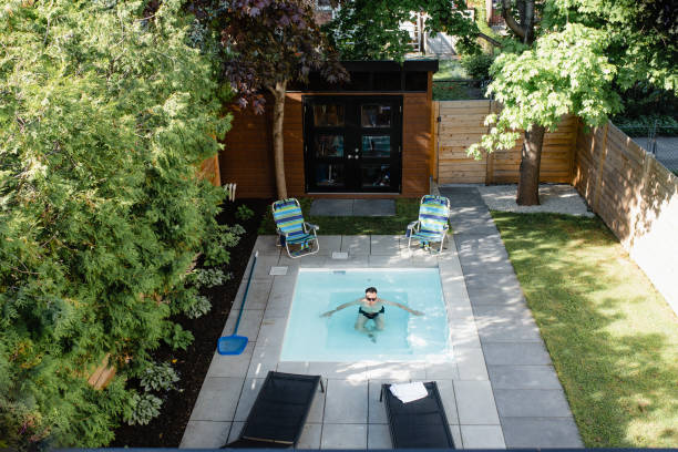 Homme qui se baigne dans la mini piscine installée dans son jardin